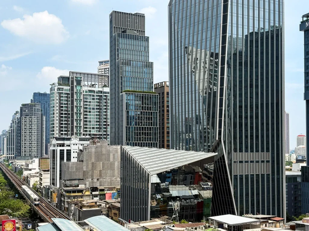 The cityscape of Bangkok from above, densely surrounded by modern highrise buildings and sky train system visible.