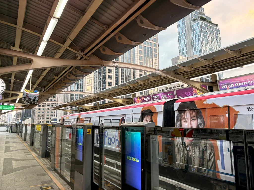 BTS Sky Train platform in bangkok. Surrounded by highrise and filled with colors of advertisement.