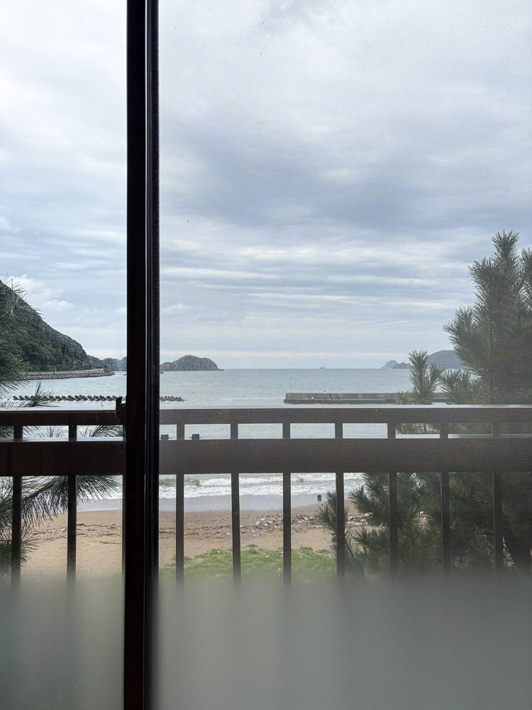 The sea view of Shitsumi in obama from a sea side hotel room through a glass door on a cloudy day.