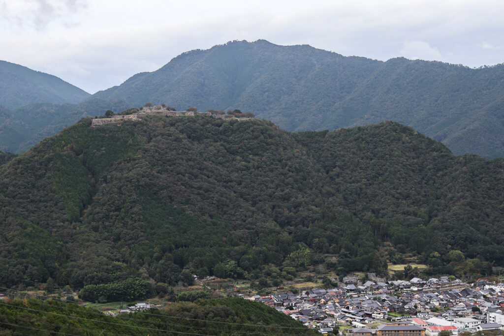 The view of Takeda Castle Ruins from the opposite mountain, showing the town below and the historicla ruin atop the mountain.