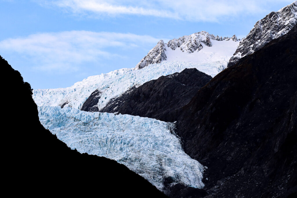 A close up of franz josef glacier from a walkway in Franz Josef, snow on the top of the alps and the glacier in good view