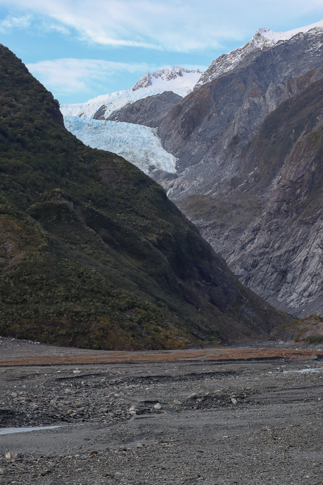 franz josef glacier in a clear day, with a little cloud above.