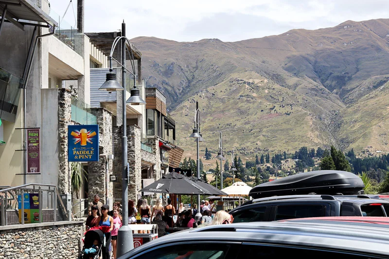Roadside carpark on Roys Bay, Ardmore St, with the view of the mountains behind the line of restaurants.