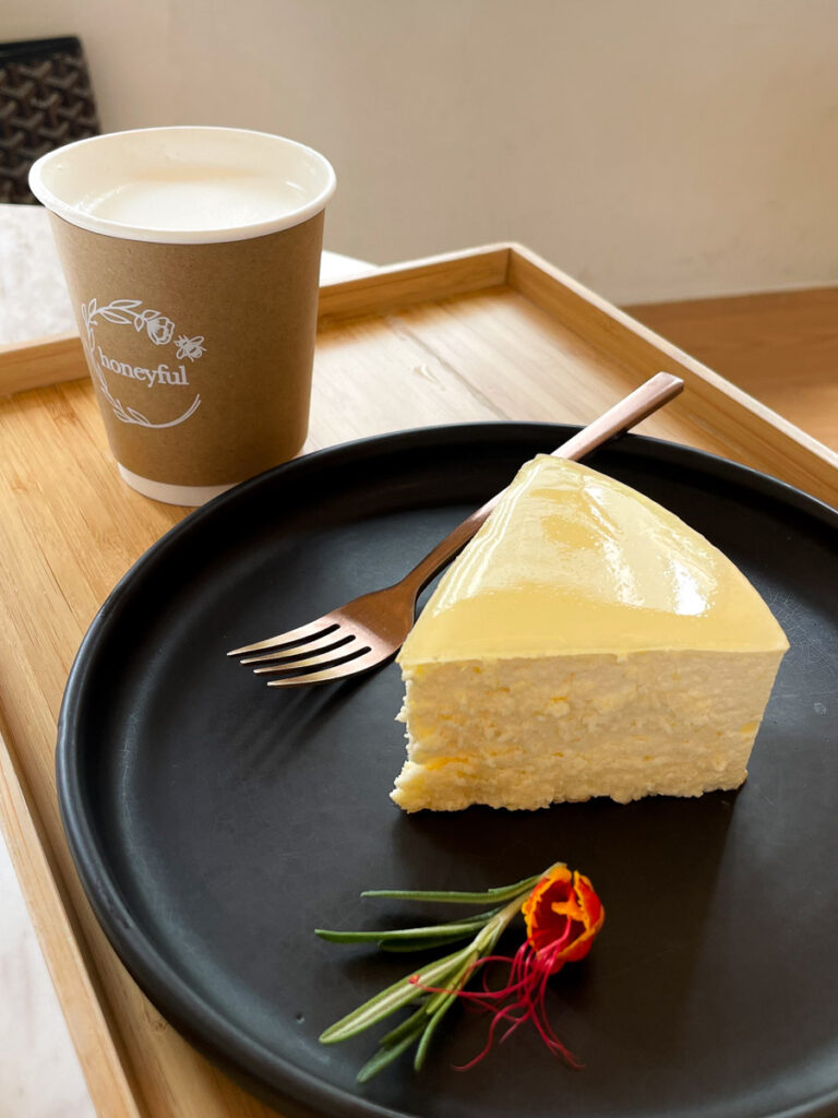 Yuzu Cheesecake at Honeyful cafe in Bangkok Sukhumvit 24, served on a wooden tray as the light hit through the window.