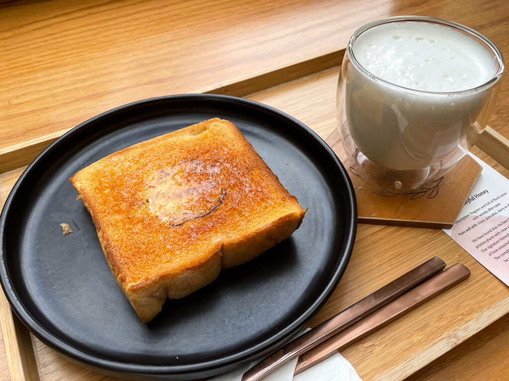 Butter and honey toast with a glass of milk at a cafe in Bangkok, served on a wooden tray.