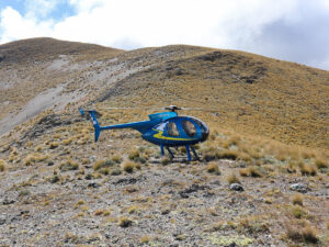 A helicopter parked on the peak of a mountain in New Zealand. The helicopter is a part of Heli Rural Tour.