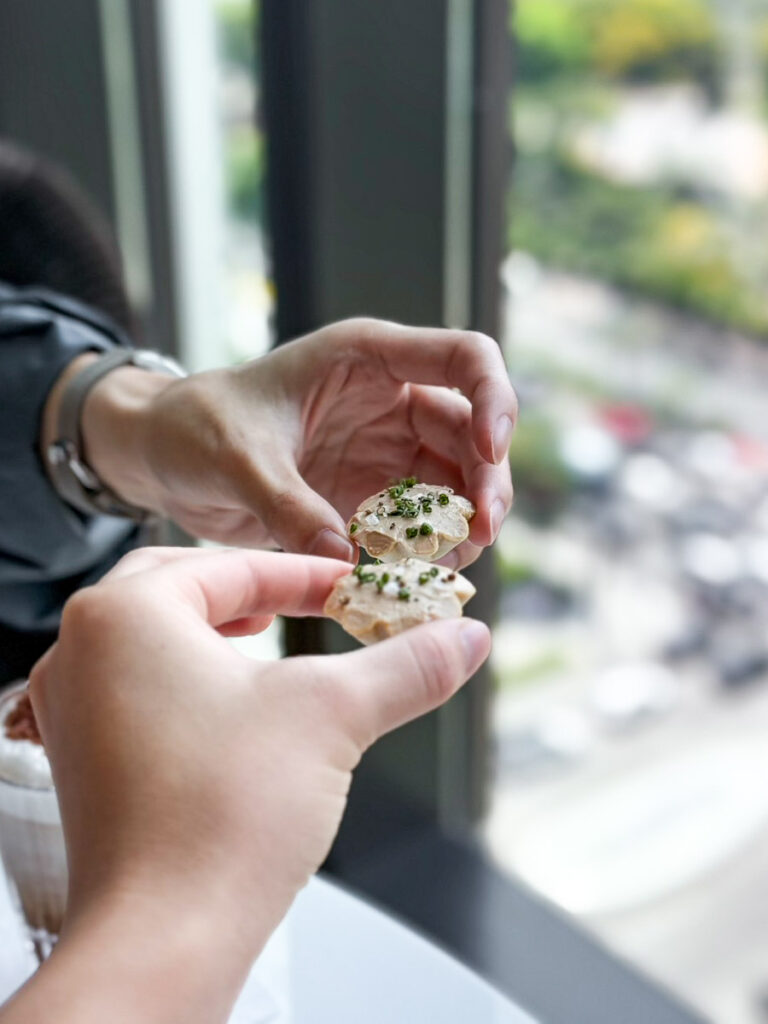 Cheering the Amuse-Bouche sitting beside a window and a view of Bangkok below, at the Ritz Carlton Bangkok Afternoon tea.