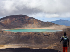 The Blue Lake on Togariro Alpine Crossing. The view during a cloudy day as a hiker hiked by the blue lake in full view from the peak.
