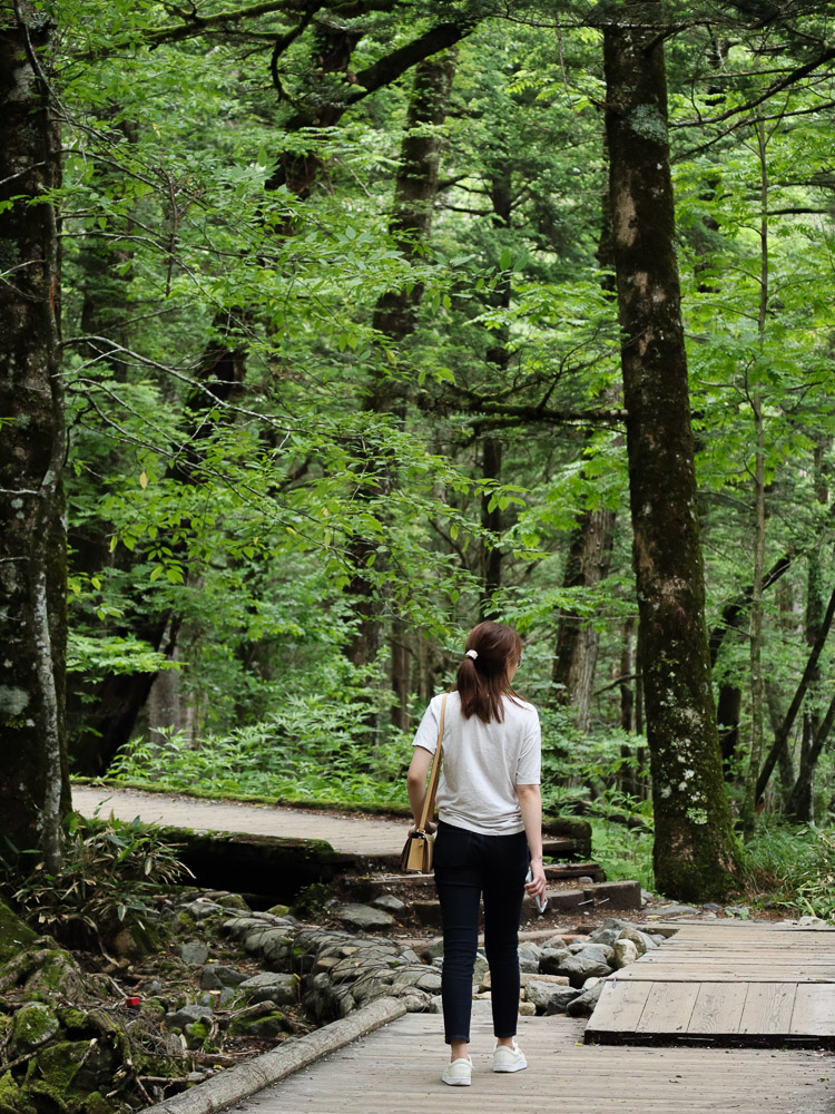 A girl walking through the forest trail at Kamikochi in the perfect summer temperature.