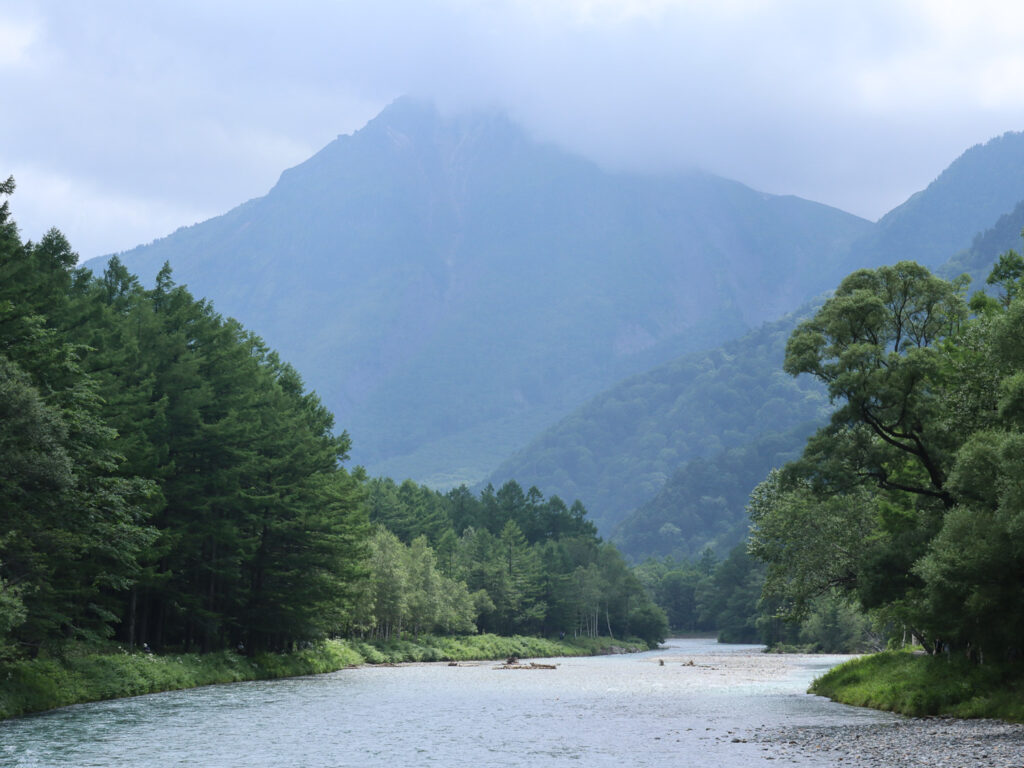 Azasa River on Kamikochi after the rain, Mount Myojin's peak is covered by dark clouds. the sun shine on a spot on the river.