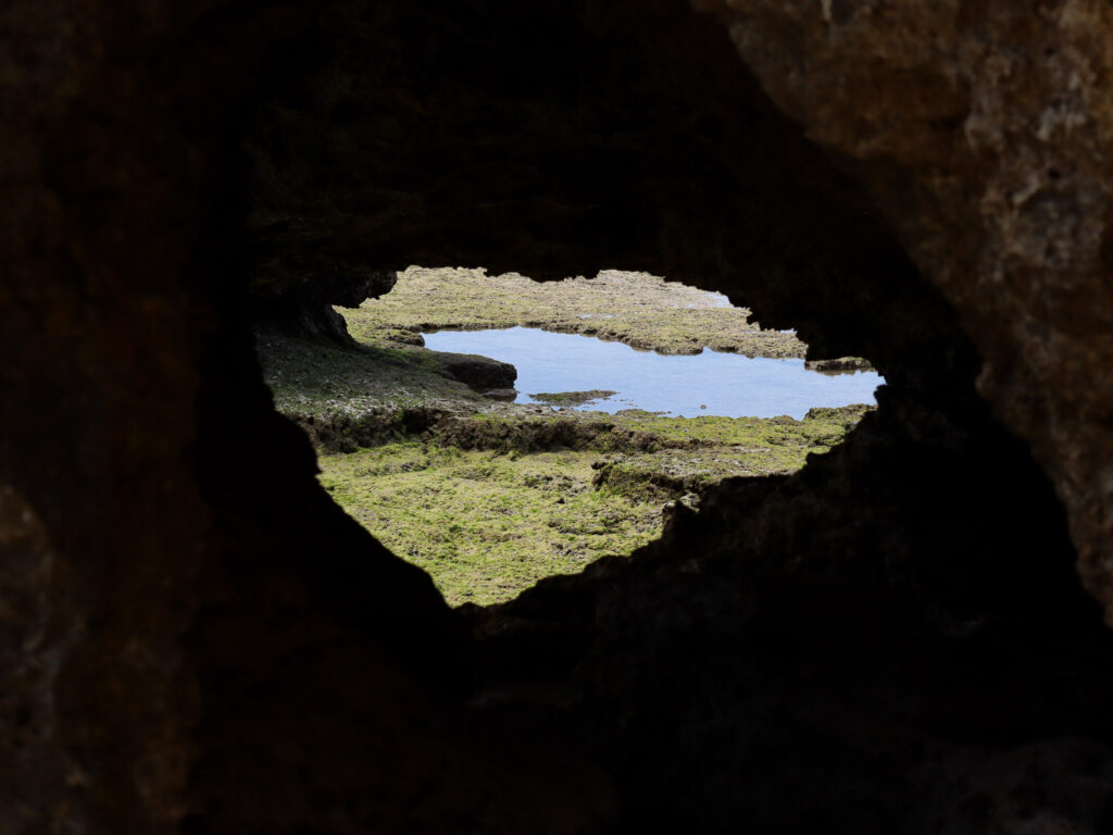 A natural rock formation with a hole in the middle. The camera shoot at the sea through the hole.