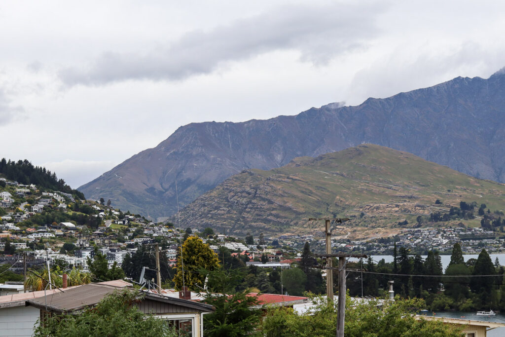 Queenstown from atop the hill on Glasgow St, the blend of human houses and the massive mountain of the area around the lake.