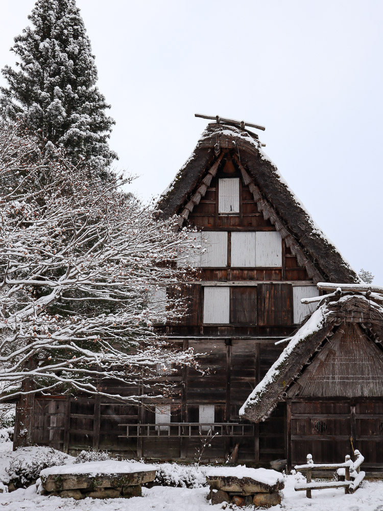 A focused shot of Gassho-zukuri farmhouse at Hida no Sato museum during winter snow. The whole museum is coverd in white.
