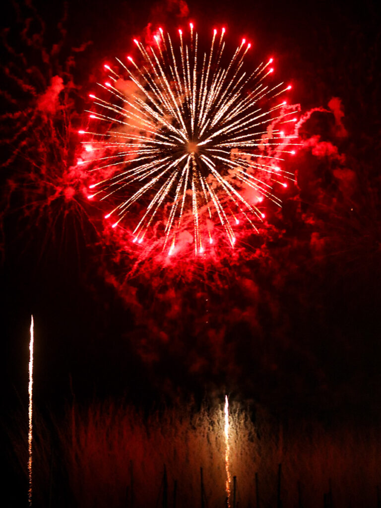 A large brilliant red firework as it explode in the night sky of Okinawa, a part of Ryukyu Kaiensai Firework Festival.