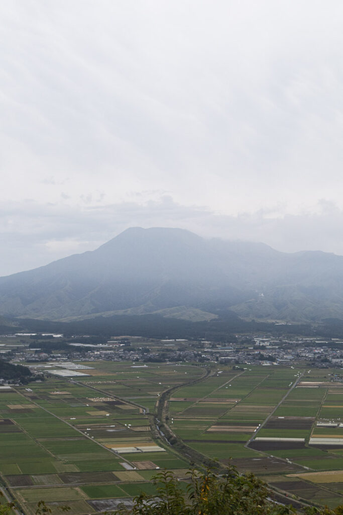 A cloudy day at Aso mountain and its valley, a neatly alligned farmland and the mountain behind.