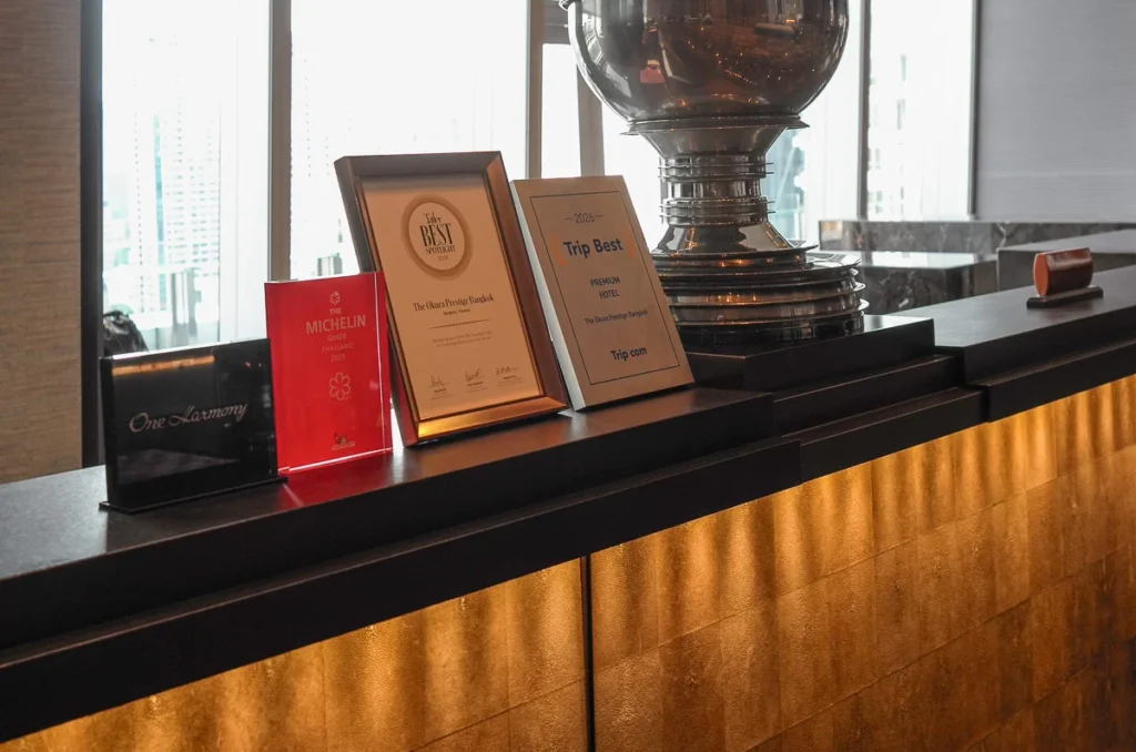 Okura Prestige Bangkok 24th floor lobby counter endowed in gold accent with the hotel's awards on display.