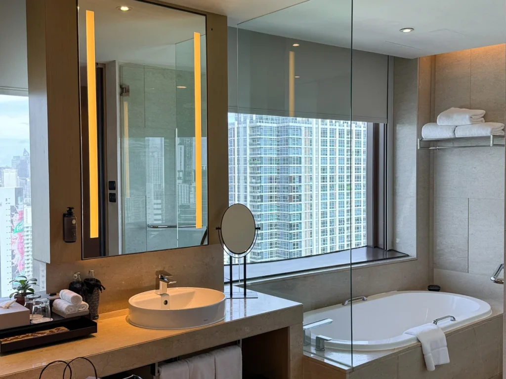A bathroom with a view overlooking Bangkok's city center area at a corner room of Okura Prestige.