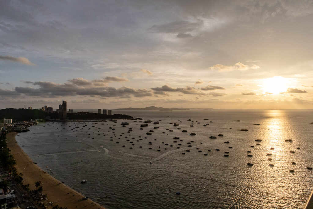 The golden hour sunset at Pattaya beach, a view covering a wide area, half of the Beach Road and the far island in the sea.
