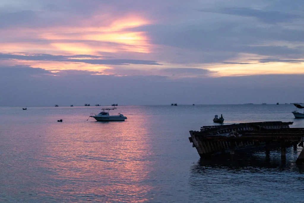 A calming view of the beach in Pattaya, the pink sunset shone through halfway as the cloud cover the other half.