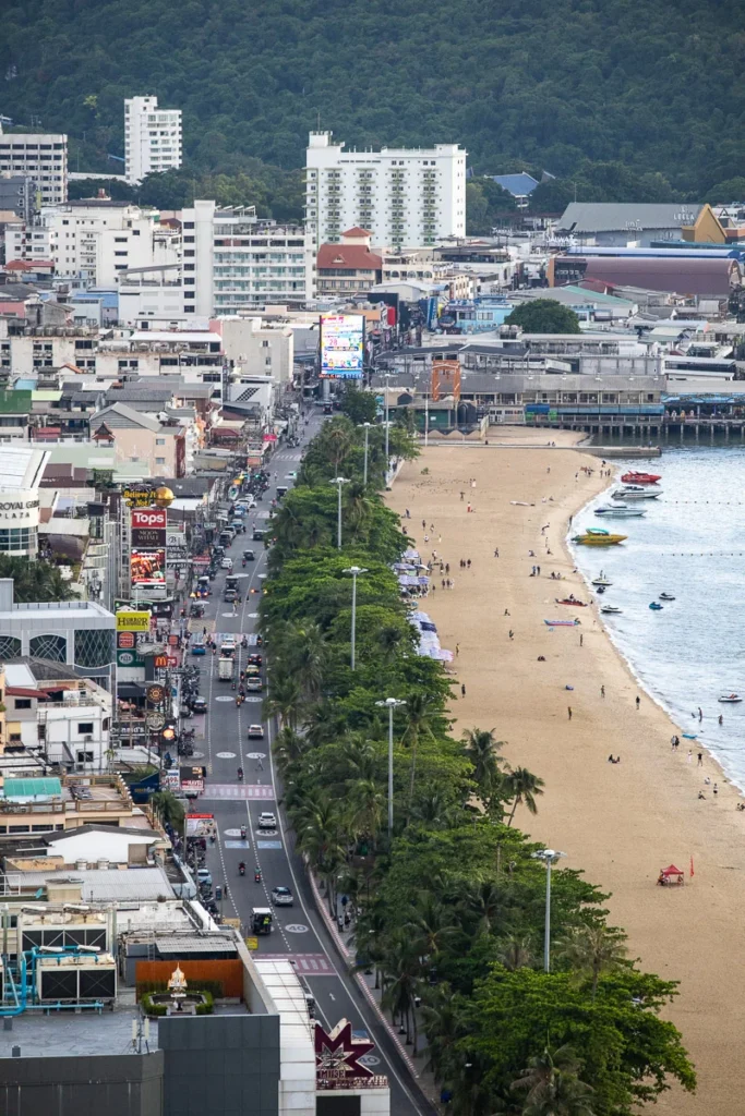Pattaya Beach, a lively atmosphere, the street lined with shops and people playing on the beach, a view from above.