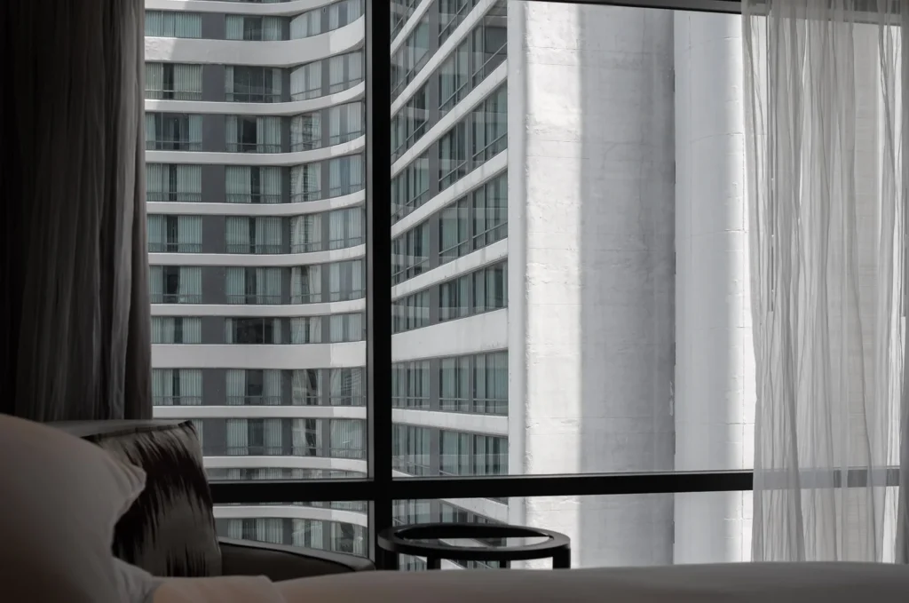 A window looking out to another window of the opposite hotel building, a view of the modern city.
