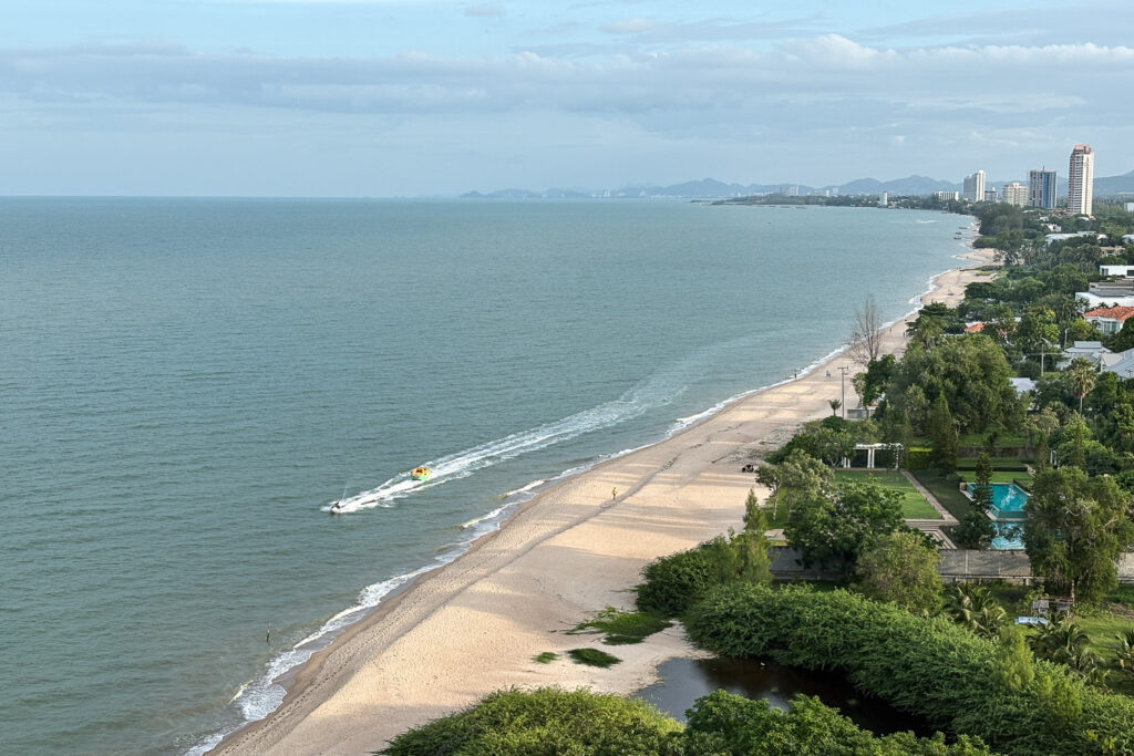 The afternoon of Cha-am beach, looking towards Hua Hin in the distance, as light cast shadows on the sand.