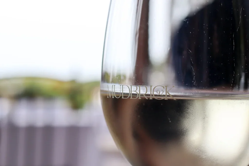 White wine in the glass with Mudbrick etched on the side.
