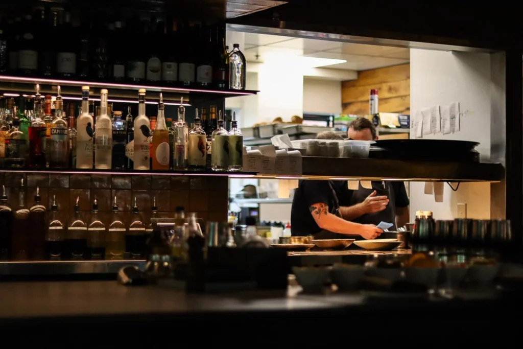 The opening into the kitchen behind the bar at Rātā Restaurant during a busy dinner service.