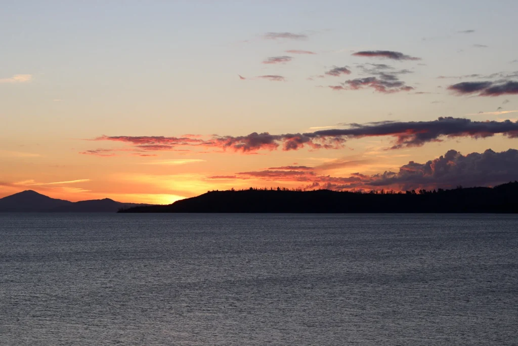 A majestic orange sunset at Lake Taupō, one of the views that make New Zealand worth visiting.