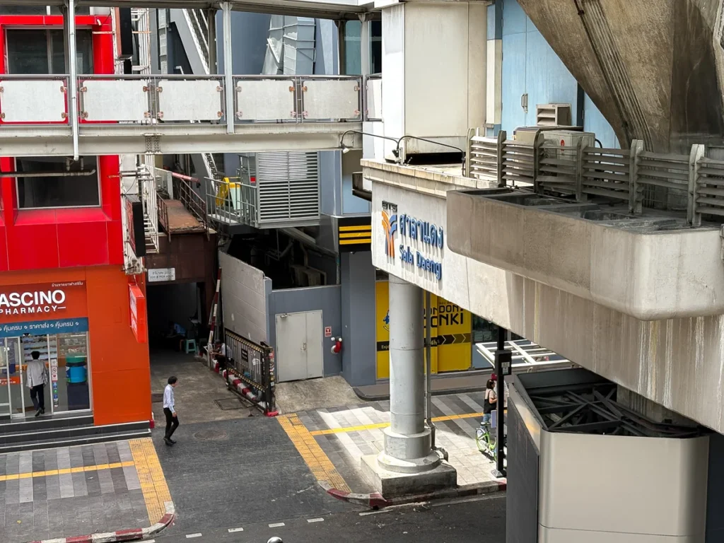 Sala Daeng BTS station during midday as light shines through the gaps between buildings.