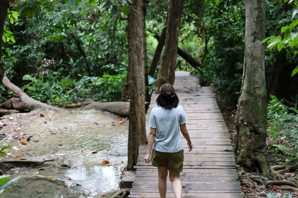 a girl hiking Erawan Falls, surrounded by nature.