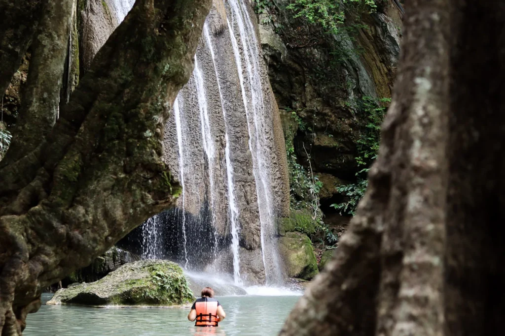 The third level of Erawan Falls, the towerinf waterfall make the people down below look small.