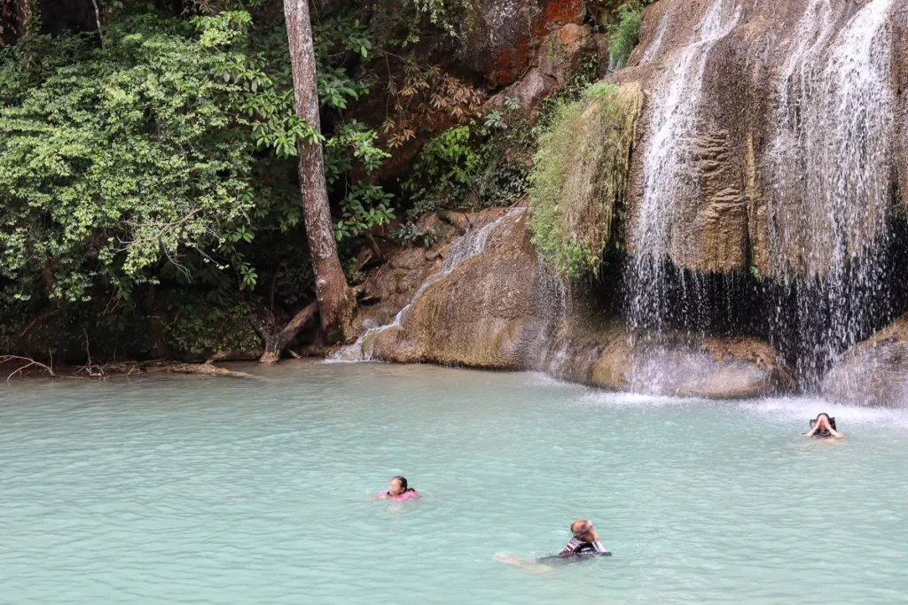 People enjoying a swin in the clear blue water of Erawan Falls