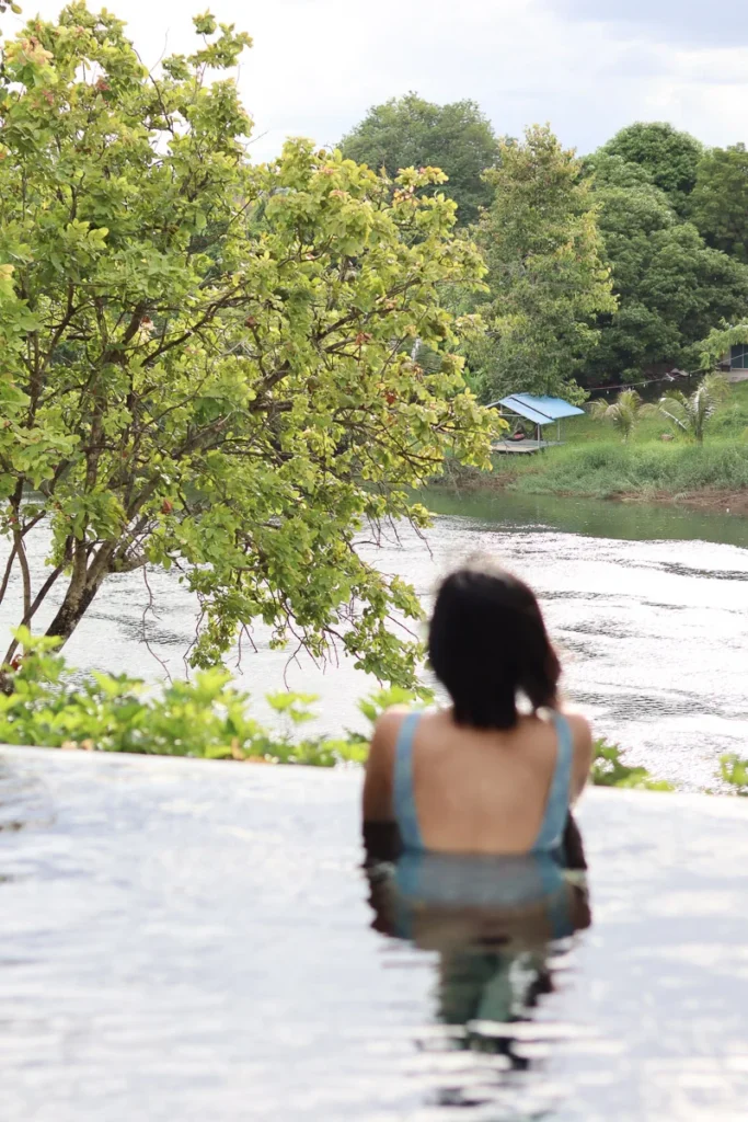 A girl in a pool villa looking out to the river at Tara Villa, Kanchanaburi.